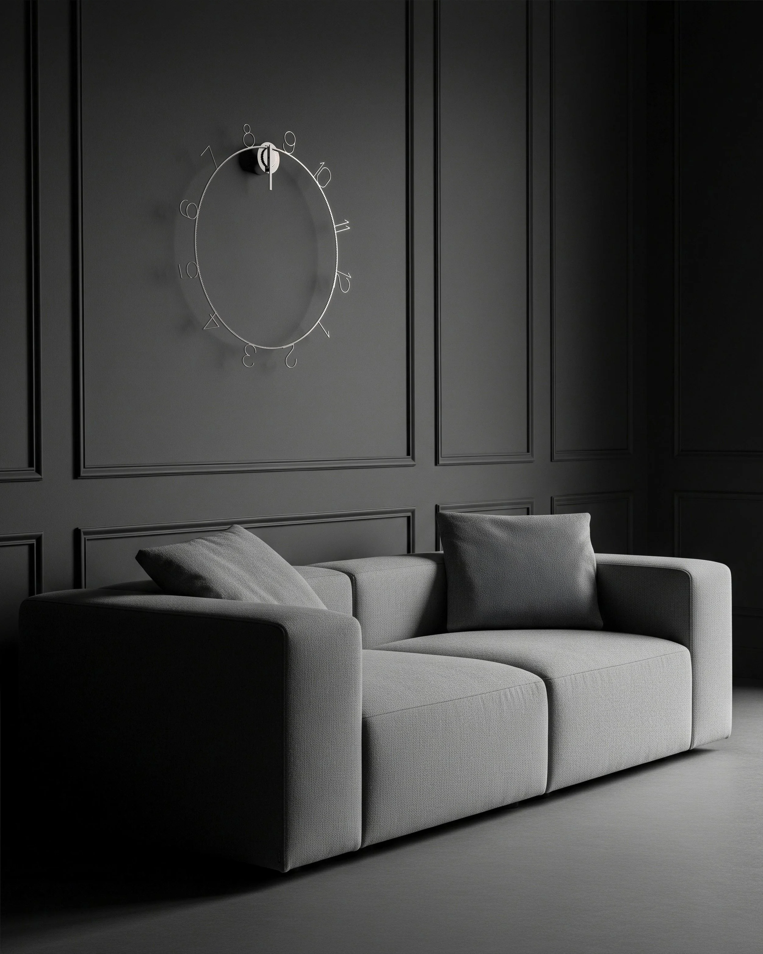 A modern gray sofa with two matching pillows, set against a dark wall with decorative paneling and a unique wall clock with a minimalist design.