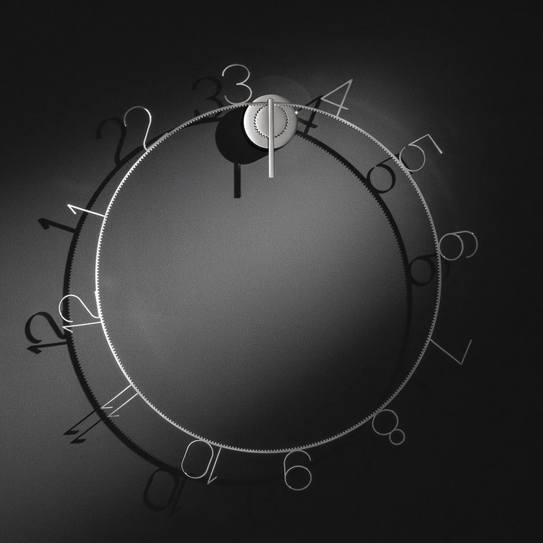 A close-up of a gray mechanical timer or stopwatch set at 12 o'clock, with a textured surface and black and white markings, against a dark background.