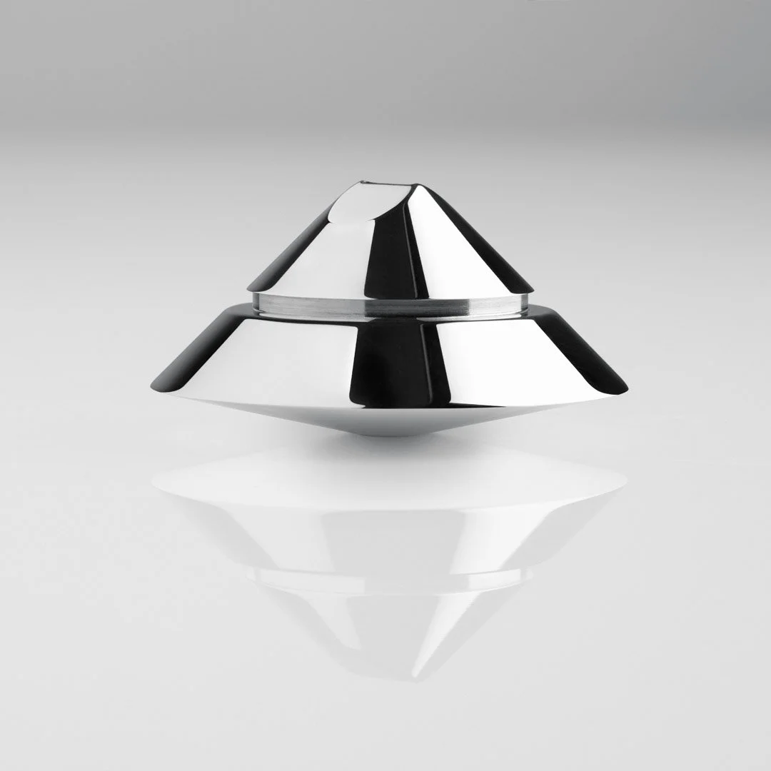 A sleek, modern, metallic black and silver container with a cone-shaped lid and rounded base, reflecting on a white surface.