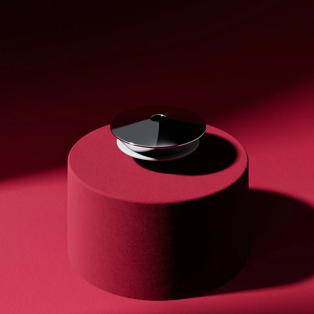 A reflective black round object placed on a red textured cylindrical pedestal with shadows cast on a dark background.