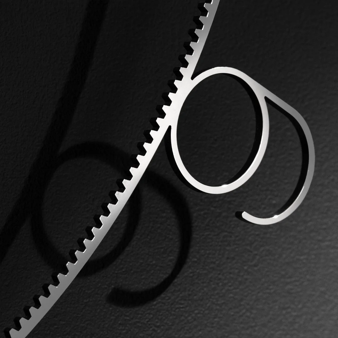 Close-up of a metal barber straight razor and a hairdressing tool on a dark textured surface, casting shadows.