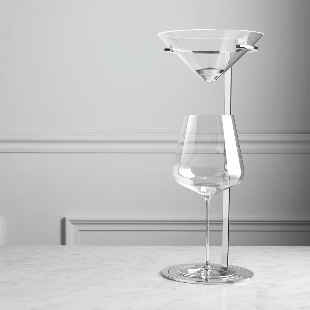 A clear glass wine glass stacked with a clear glass funnel on a white marble surface against a light gray wall.
