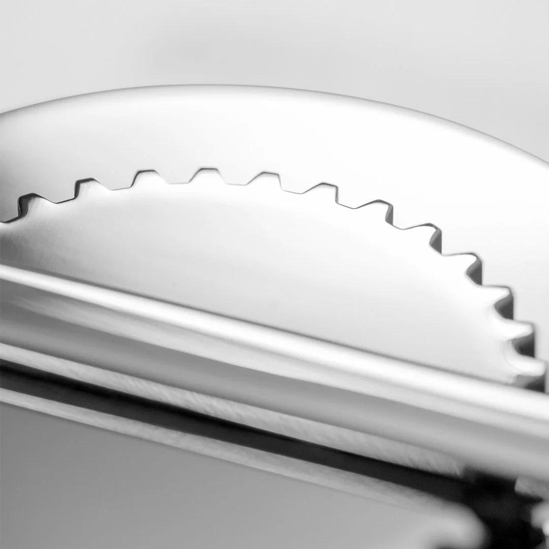 Close-up of a metallic cake slicer or bread cutter with a serrated edge.