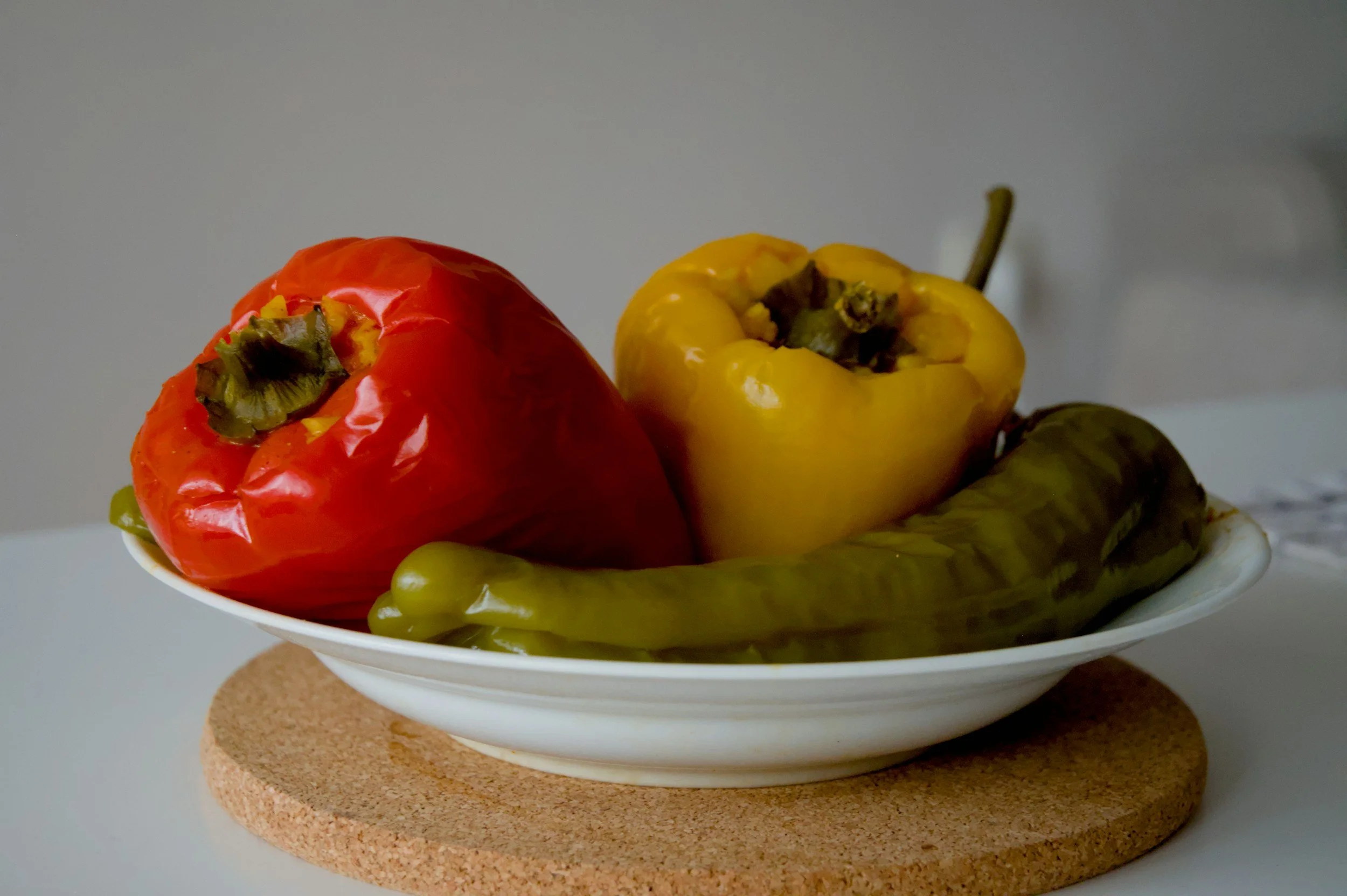 Red, yellow and long green sweet peppers in a white bowl
