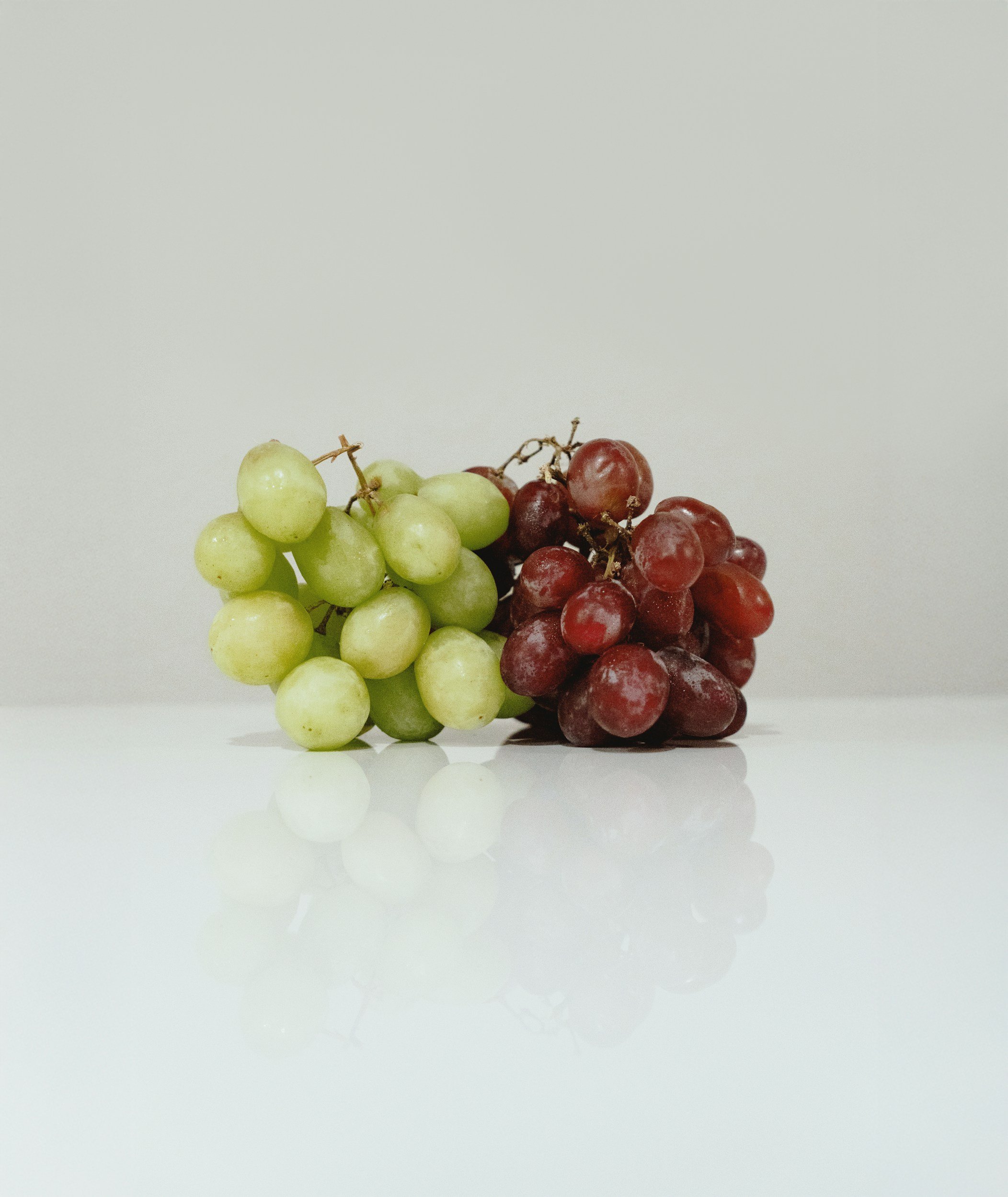 Bunches of green and red grapes together on a pale background