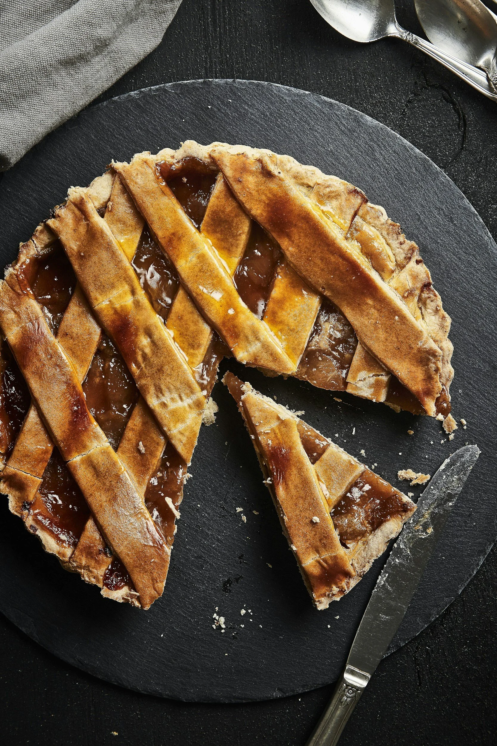 Golden lattice-topped apple pie with a slice cut out on a dark plate