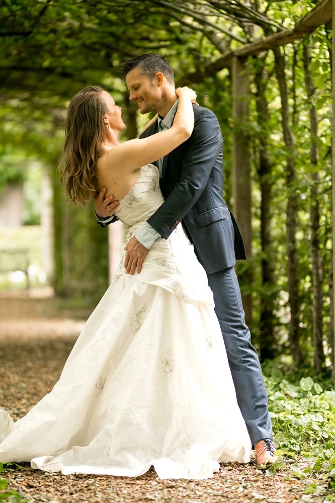 Een bruid en bruidegom dansen samen in een groen bos, ze genieten van elkaars gezelschap en zijn verliefd in deze kasteeltuin
