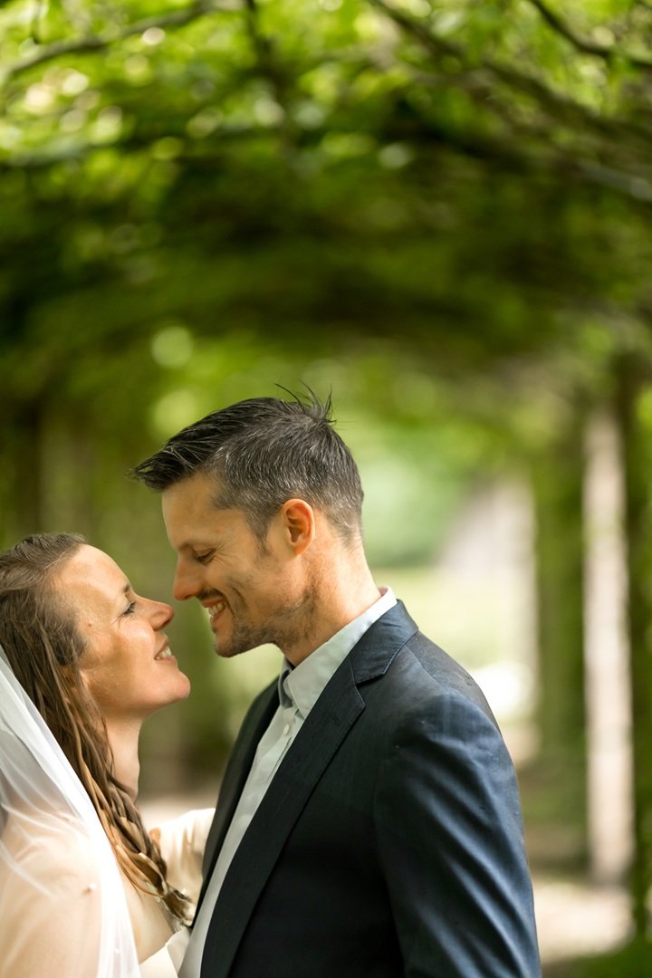 Verliefd stelletje, in trouwkleding dat zwijgend dicht bij elkaar staat, met een groene, bosrijke achtergrond, de liefde is voelbaar.