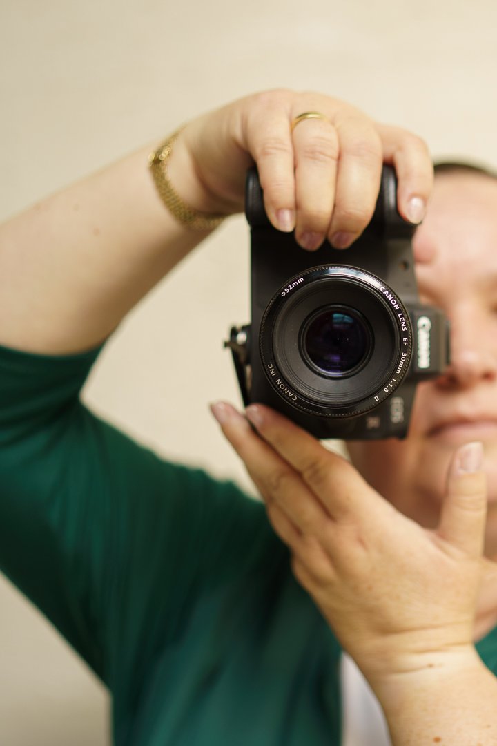 Een persoon die een camera vasthoudt en een foto neemt, met focus op de camera en de hand van de persoon.