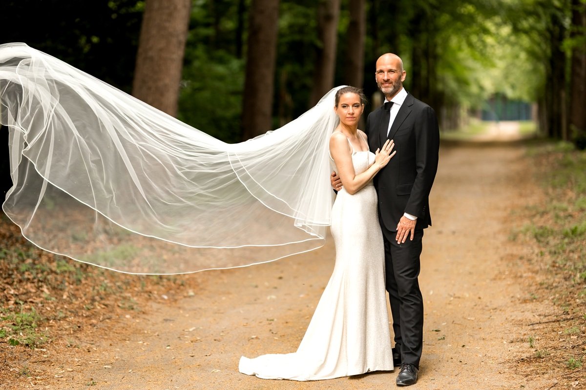 Bruidspaar samen op een mooie plek in het bos, elegante, stijlvolle foto van een mooi moment. Bruidegom in een zwarte pak en de bruid in een witte trouwjurk en sluier.