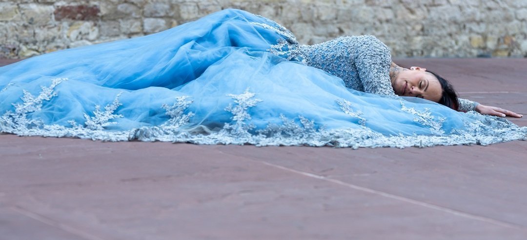Portret van een vrouw in een prachtige, blauwe avondjurk, zij ligt stijlvol op de grond van een prachtig oud gebouw. Het is een unieke, stijlvolle foto