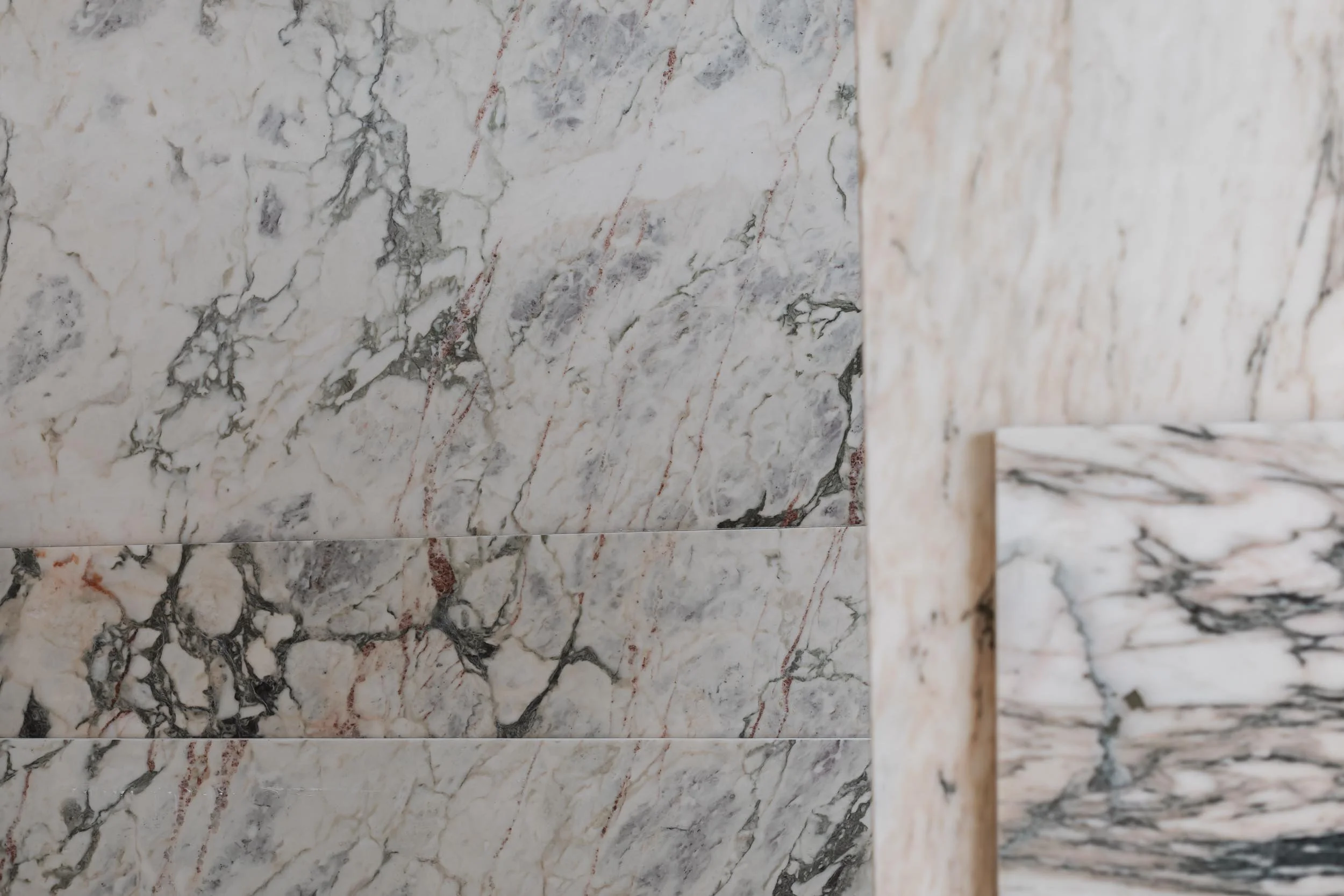 Close-up of marble tiles with black, gray, and red veining patterns.