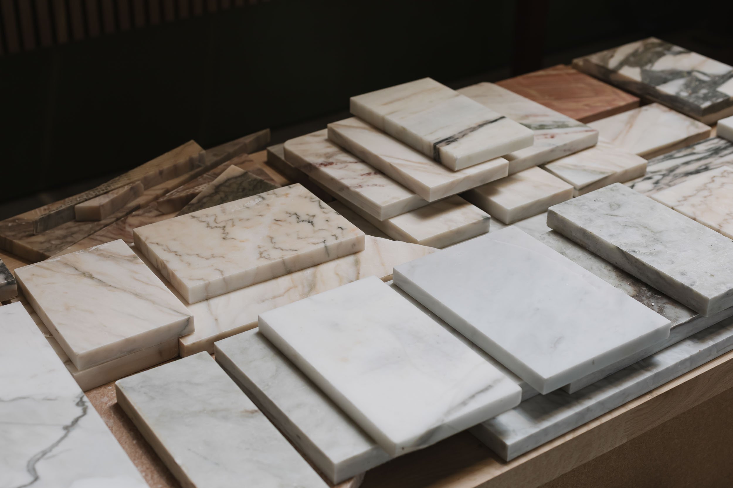 A variety of marble tiles in different colors and patterns displayed on a wooden surface.