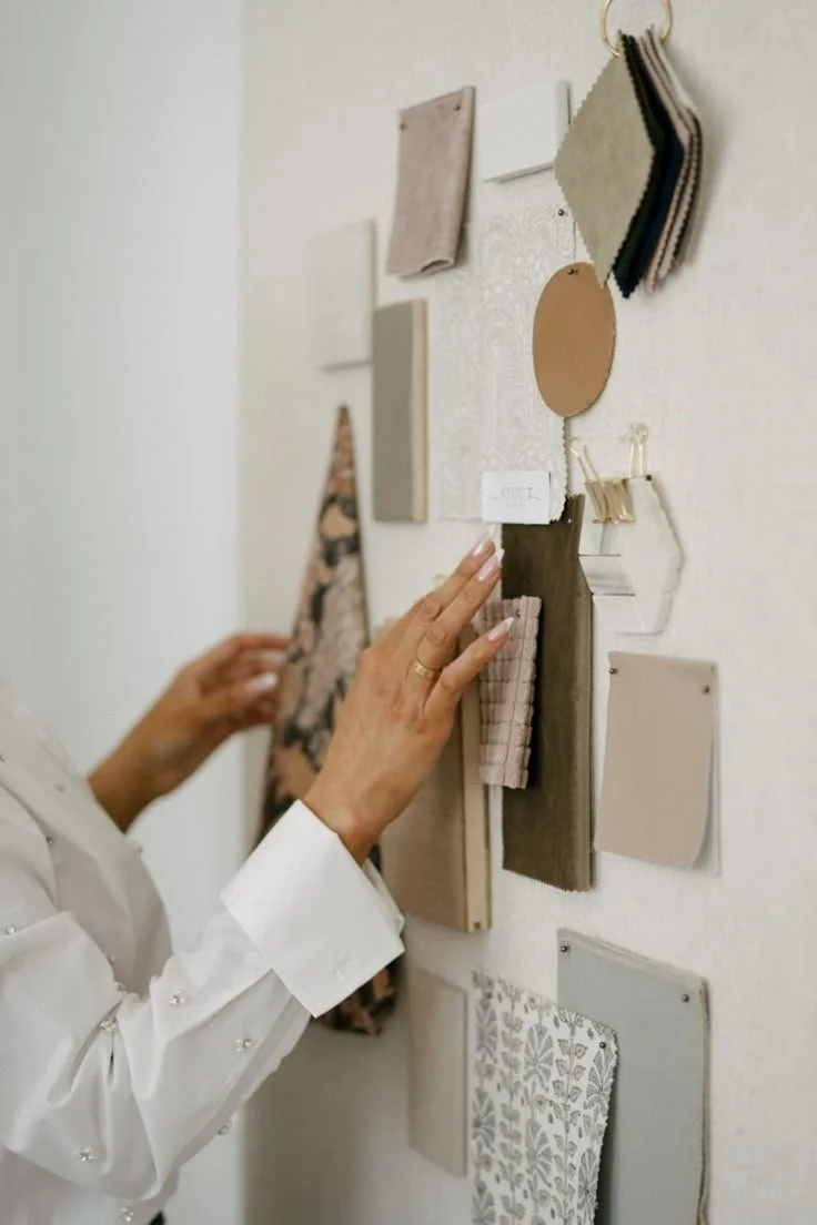 Person browsing fabric and material swatches on a wall display.