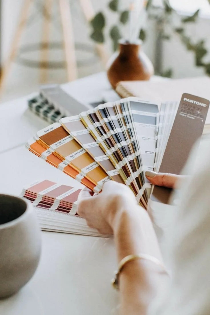Person holding color swatch fan deck with paint color samples.