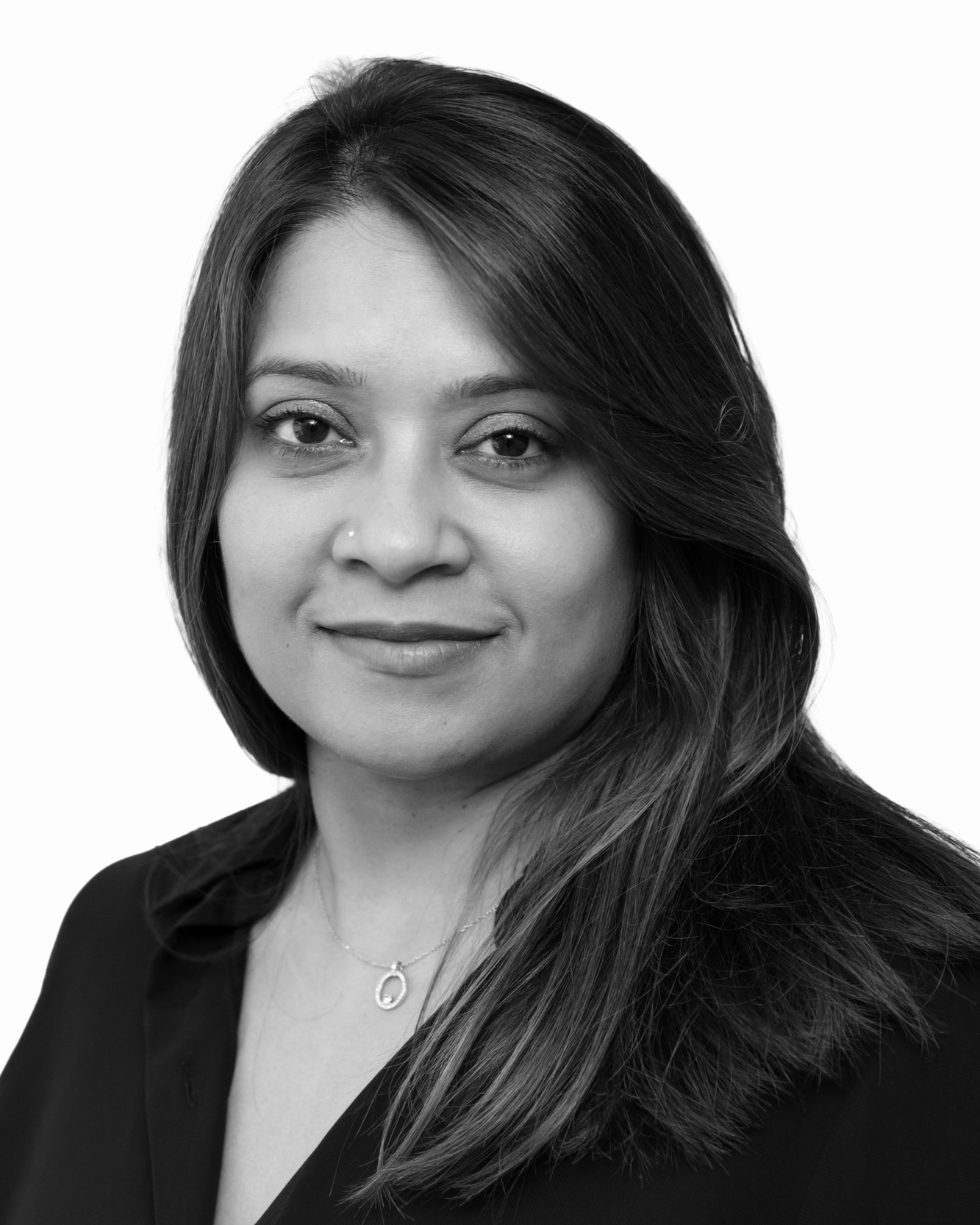 Black and white headshot of a woman with long hair, wearing a dark top and a necklace with a pendant.