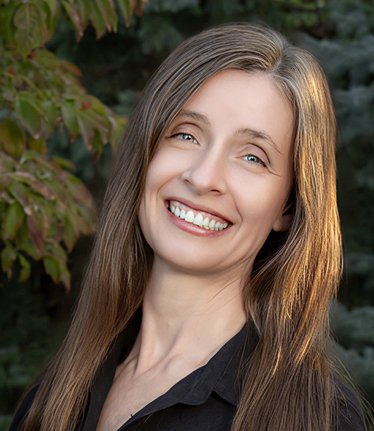 Dr. Letitia Randall, DDS, MS, headshot located outdoors, background includes green foliage.