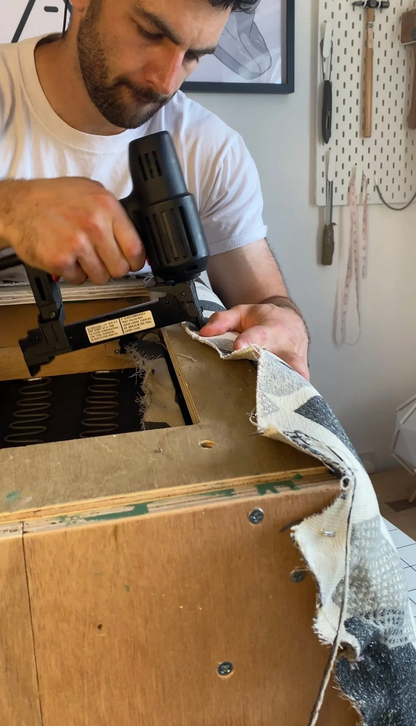 fabric being tacked onto a chair frame during the upholstery process