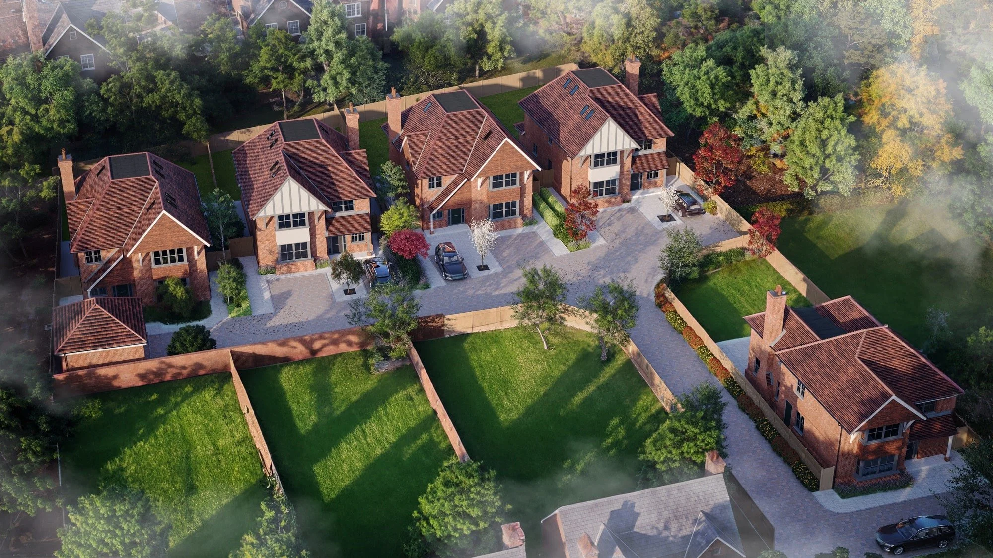 Aerial view of suburban neighborhood with several modern brick houses, driveways, parked cars, green lawns, trees, and landscaped yards.