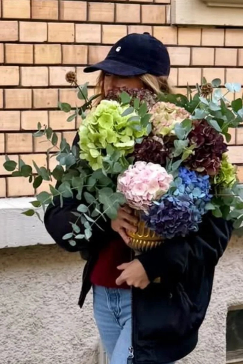 Salomé a lancé son activité de fleuriste événementiel, elle porte un bouquet de fleurs