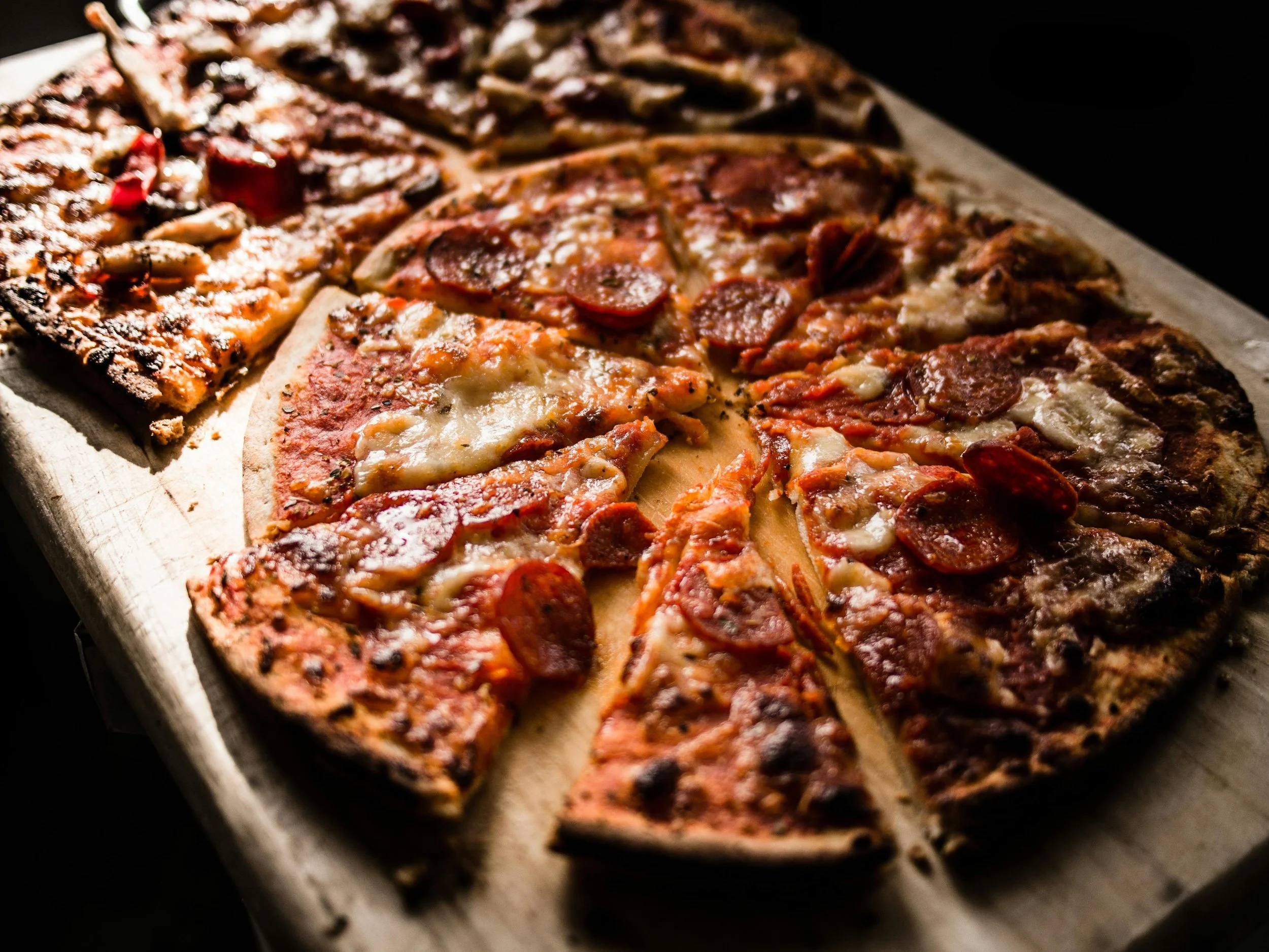 Close-up of a sliced pepperoni and cheese pizza with a side of toasted bread or garlic bread.