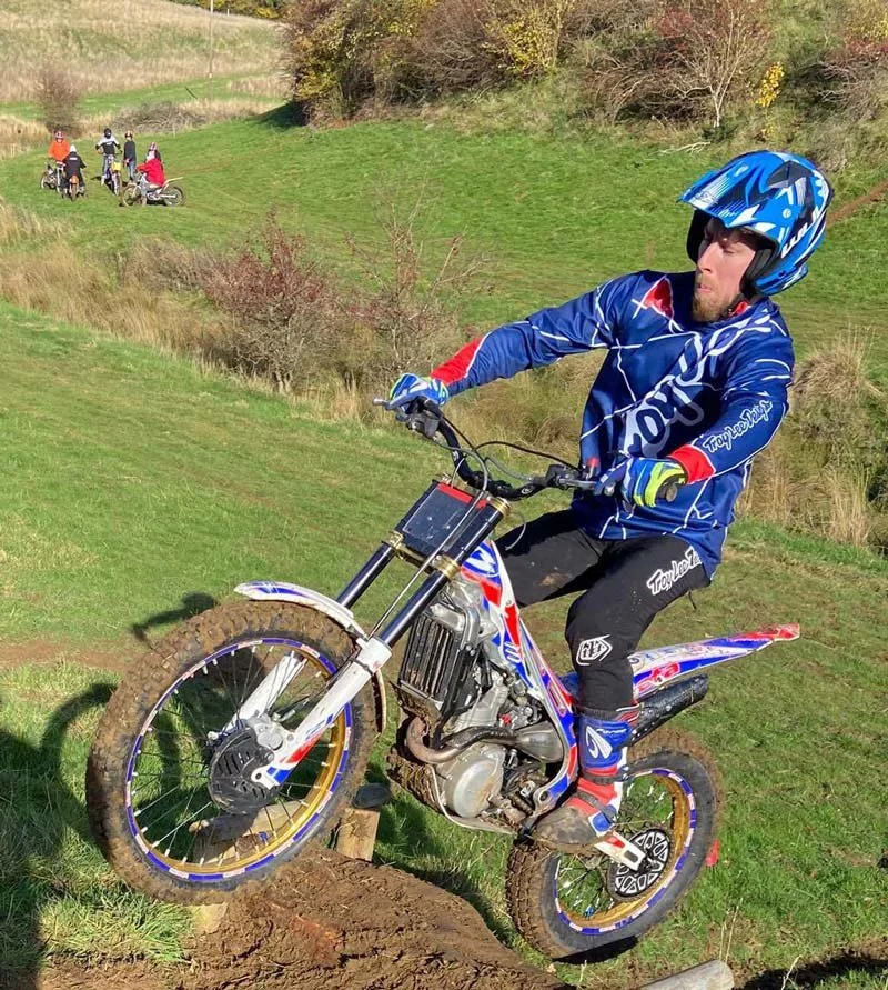 A junior rider climbing a grassy bank while maintaining balance on the bike.