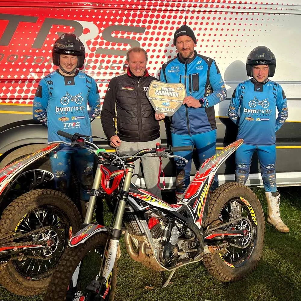 TRS team riders at Magnum Trials Centre standing with trials bikes during event day.