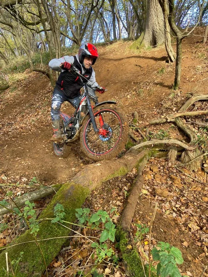 A rider navigating a steep, loose dirt descent through roots and woodland terrain.
