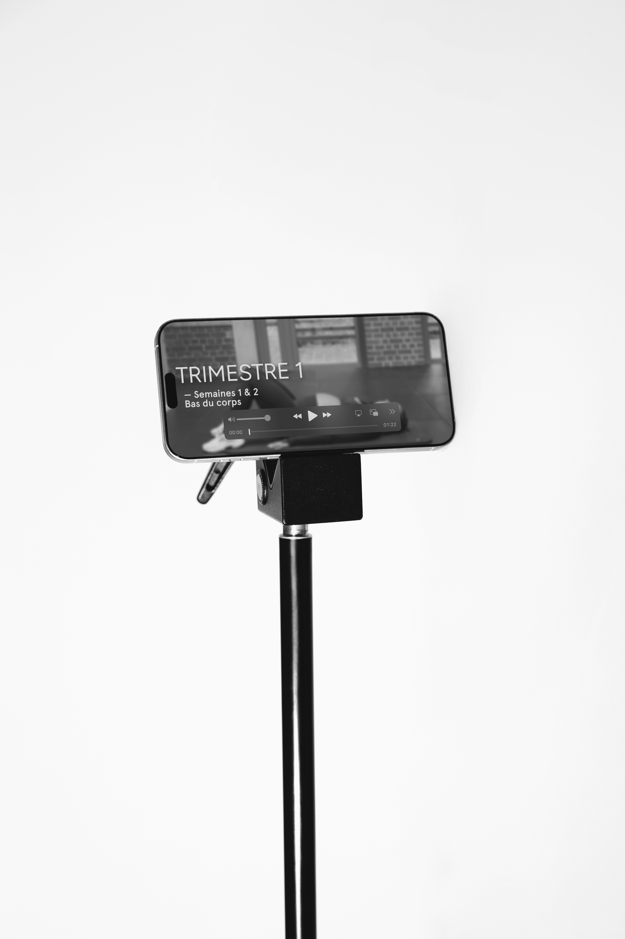 Un téléphone posé sur un support, affichant un programme d'exercices sportifs pour le premier trimestre.