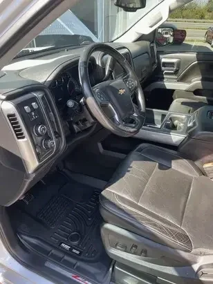 Interior of a Chevrolet Silverado truck showing the driver's seat, steering wheel with Chevrolet logo, dashboard, and center console.