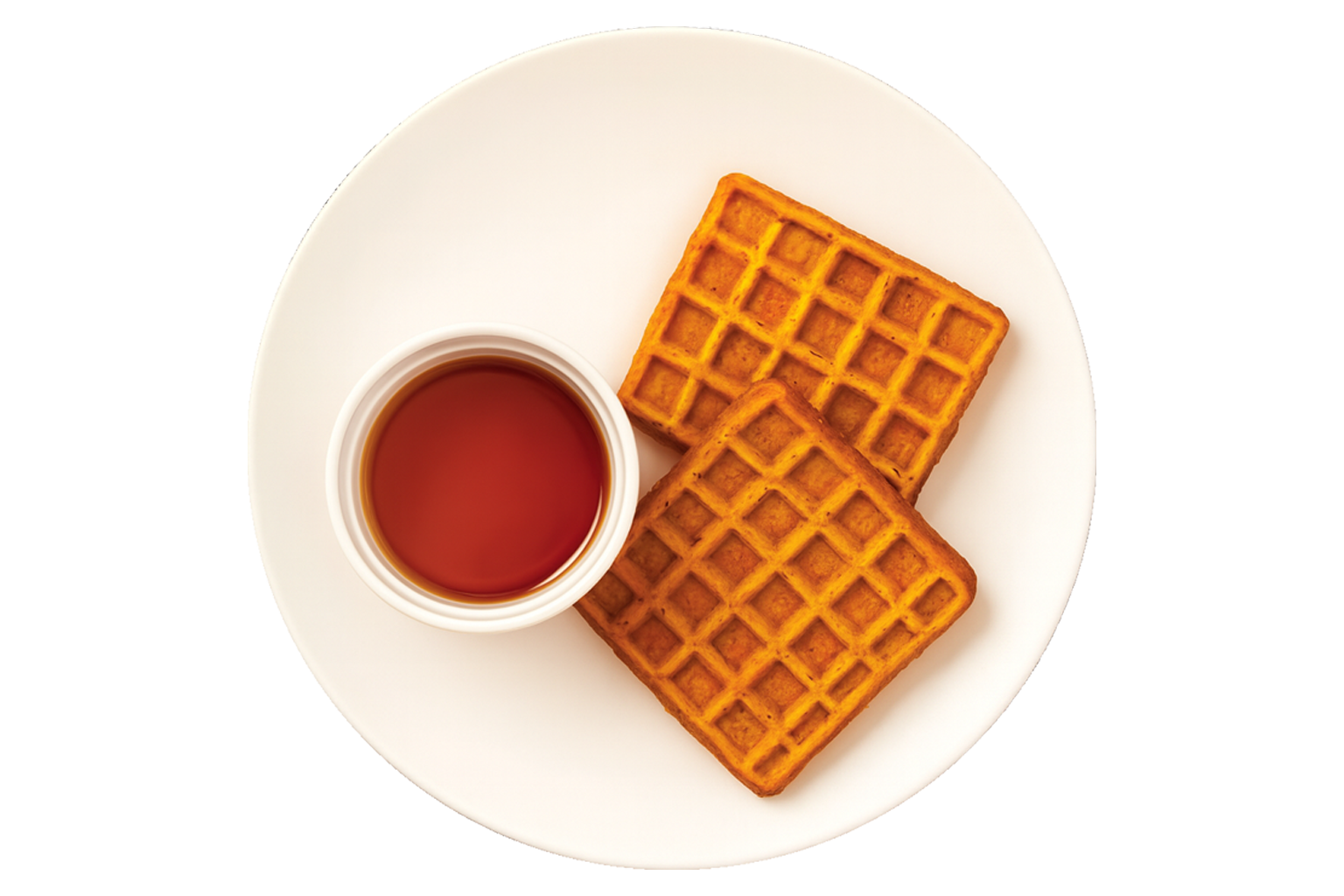 Two golden-brown waffles on a white plate with a small white cup of syrup.