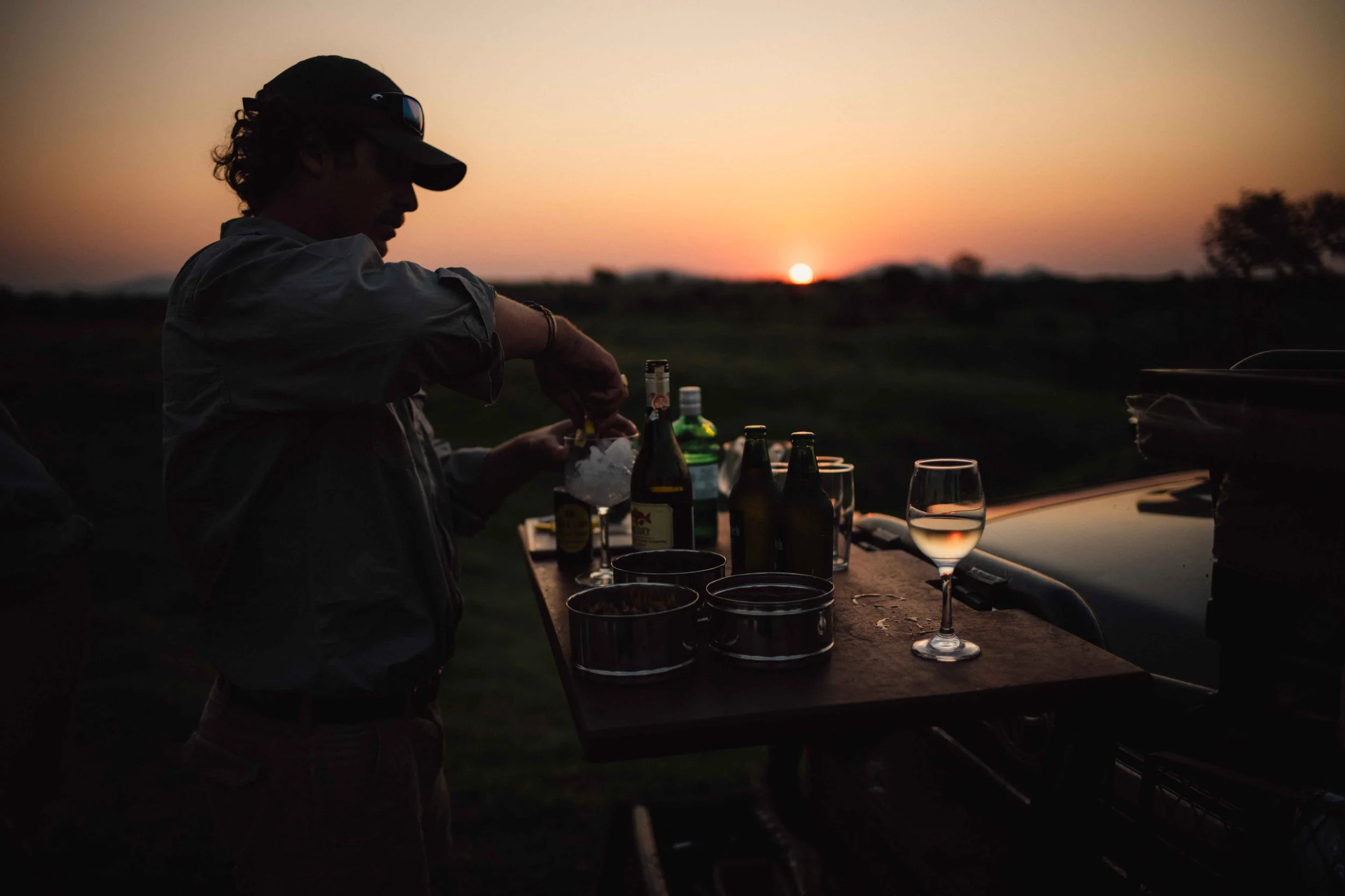 Guests enjoying sundowner drinks at a private lodge during sunset.