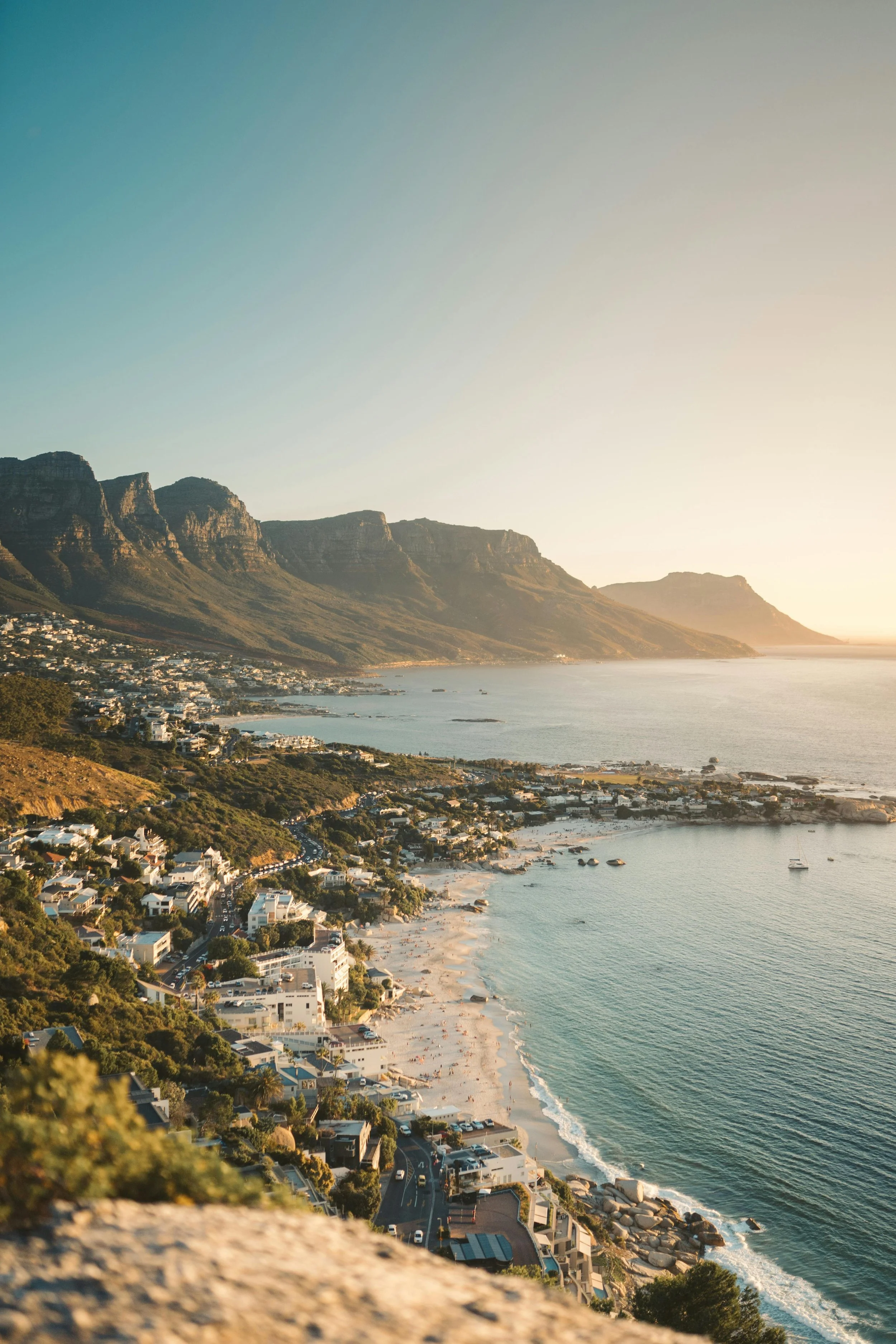Golden-hour aerial view of Camps Bay and the Twelve Apostles mountains.