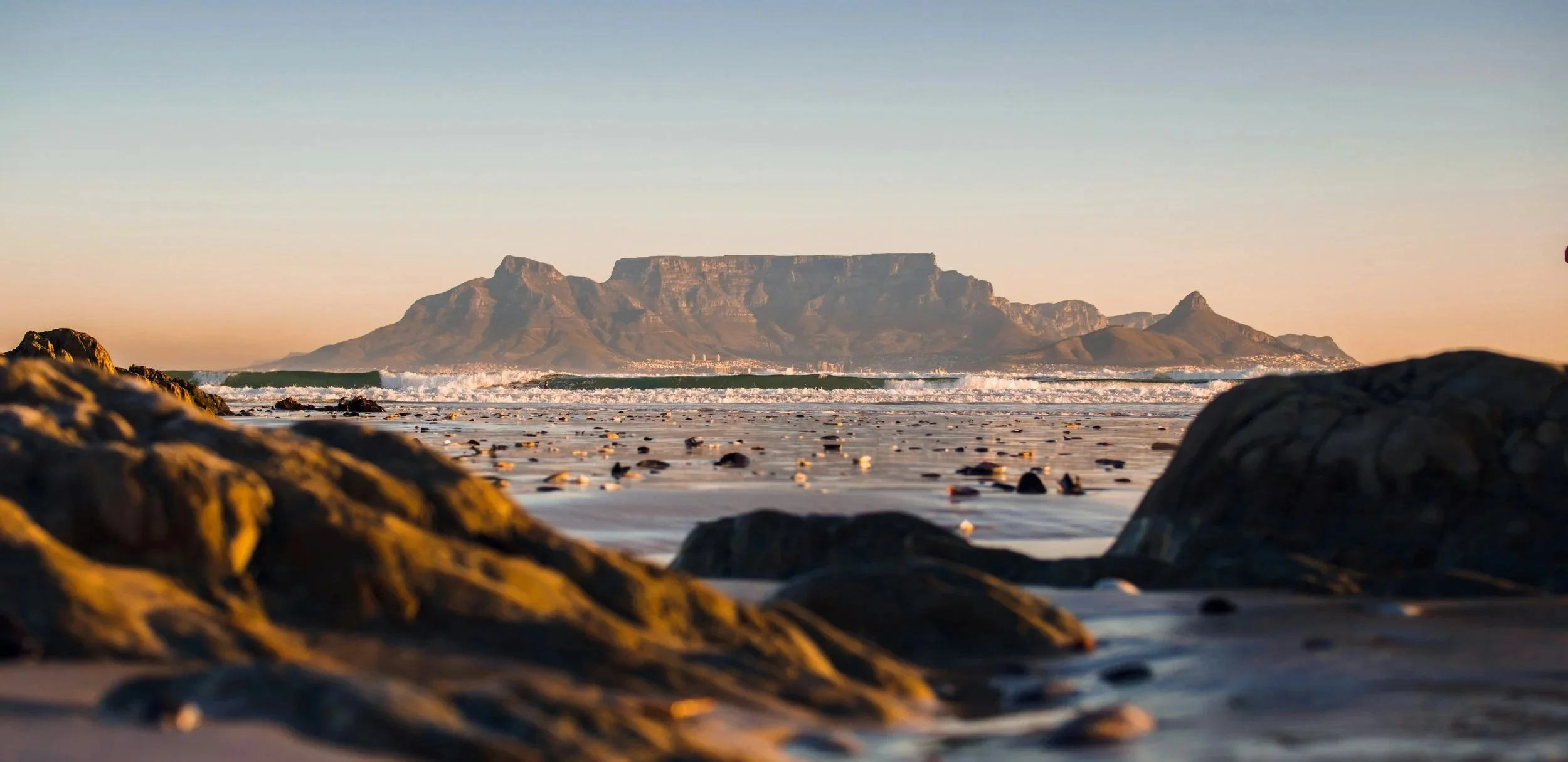 Coastal view of Cape Town’s Table Mountain at sunset.
