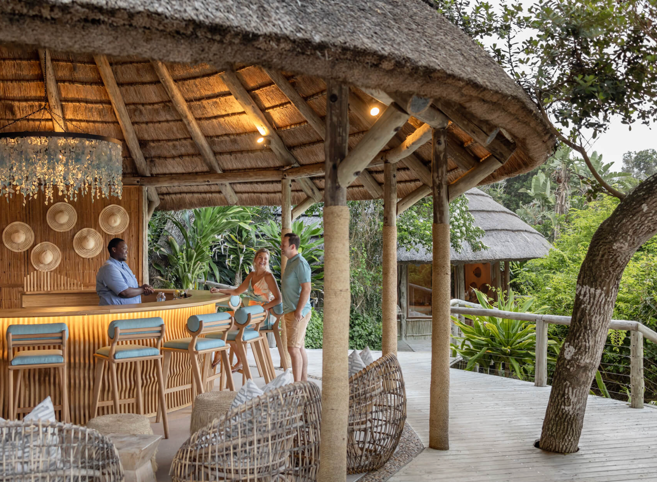 Couple enjoying drinks at a Tonga Beach Lodge bar surrounded by lush greenery.