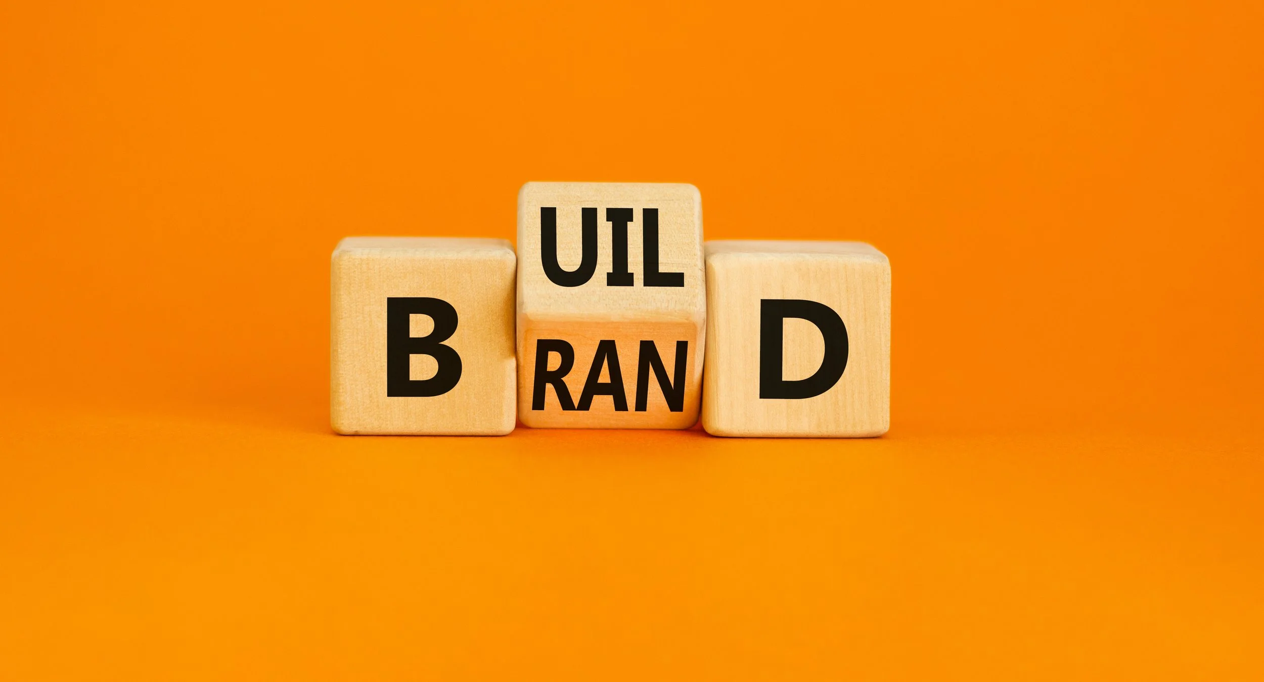 Wooden blocks spelling out "UI BRAND" on an orange background.