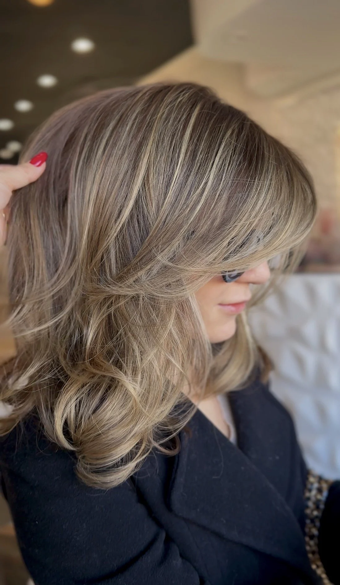 Close-up of a woman with shoulder-length, wavy, blonde hair and side-swept bangs.