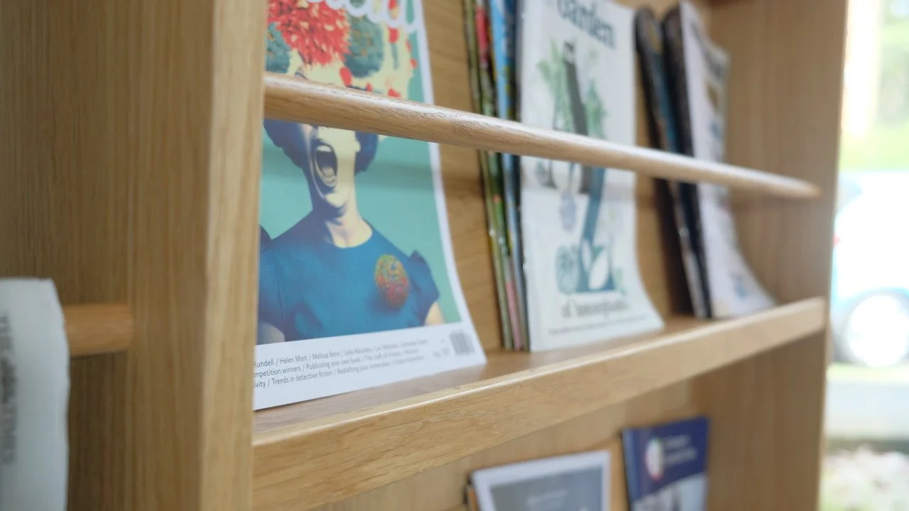 A wooden bookshelf with various magazines or comic books displayed, featuring a colorful cover with a woman with a large hairstyle and open mouth.