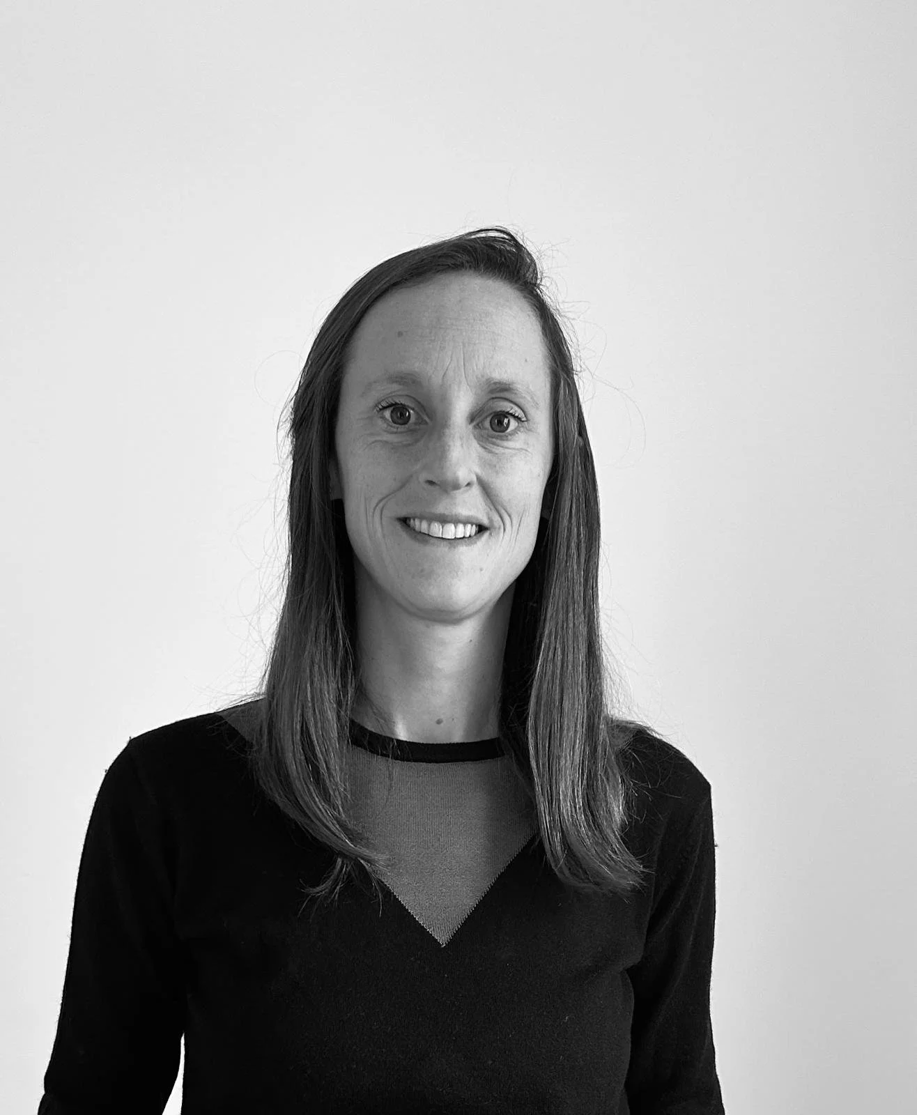 Black and white portrait of a woman with long hair, smiling, wearing a sweater with a geometric pattern.