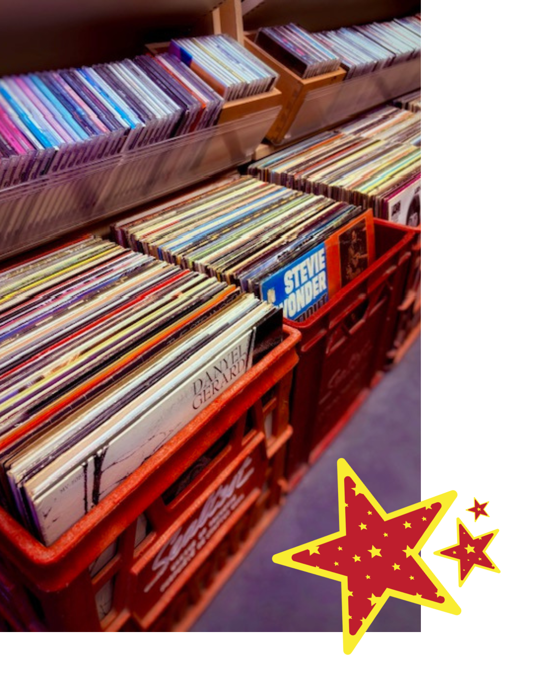 A display of vinyl records in red crates inside a store, with some records leaning against a display shelf, including a visible copy of Stevie Wonder's album.