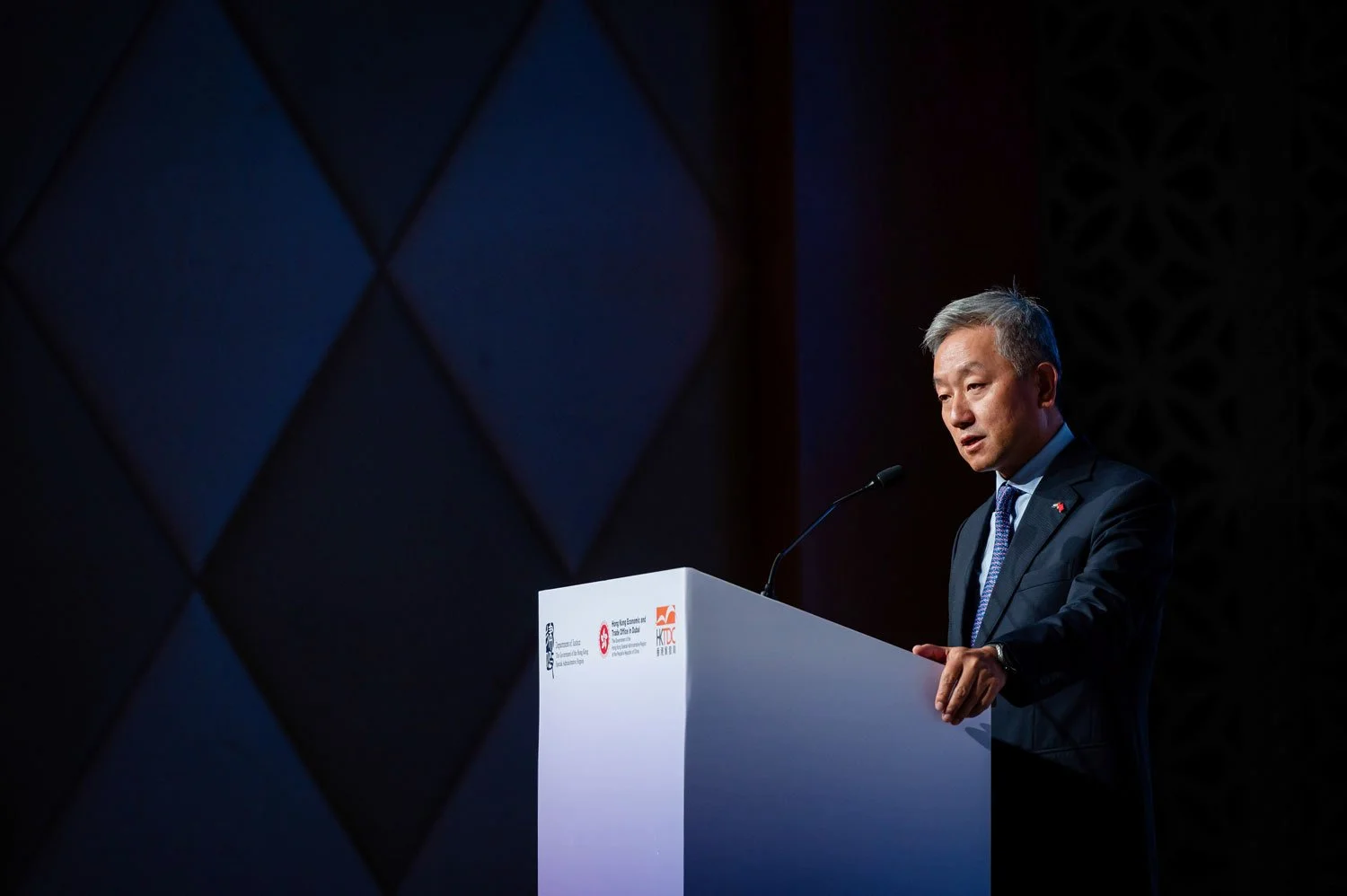 A man in a dark suit and tie standing at a podium giving a speech.