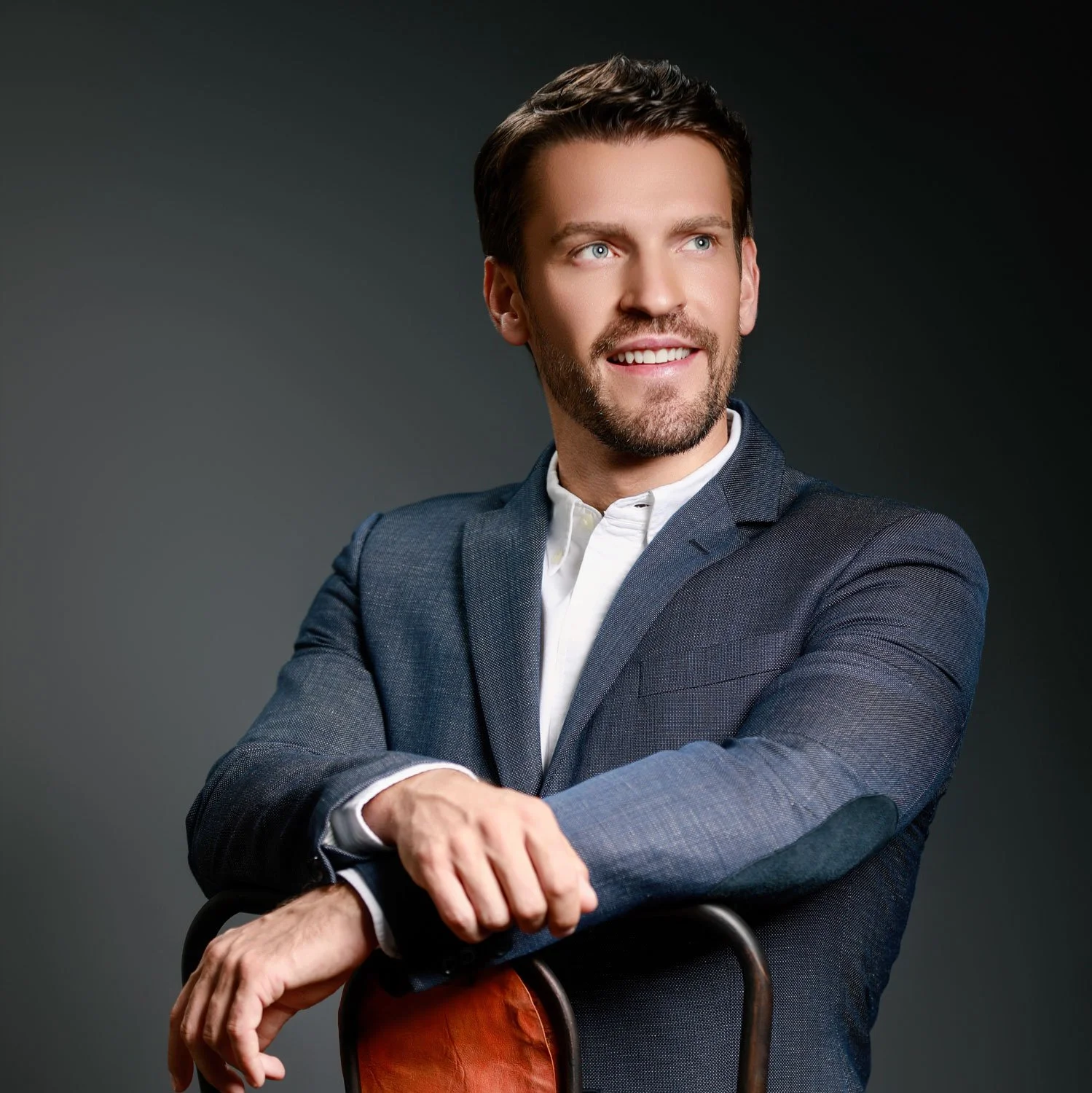 Professional portrait of businessman seated on chair photographed for corporate branding and executive profile photography.
