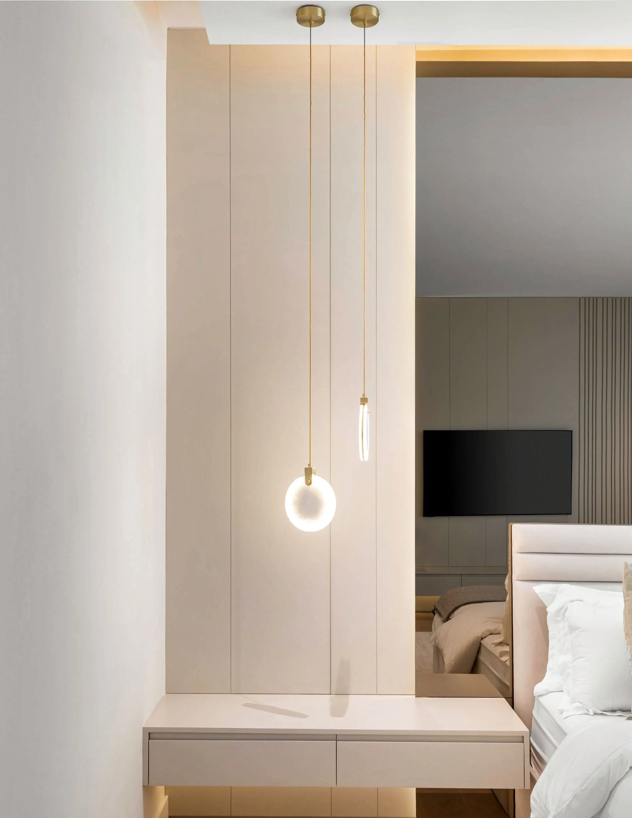 Modern bedroom with two hanging pendant lights and a mounted flat-screen TV.