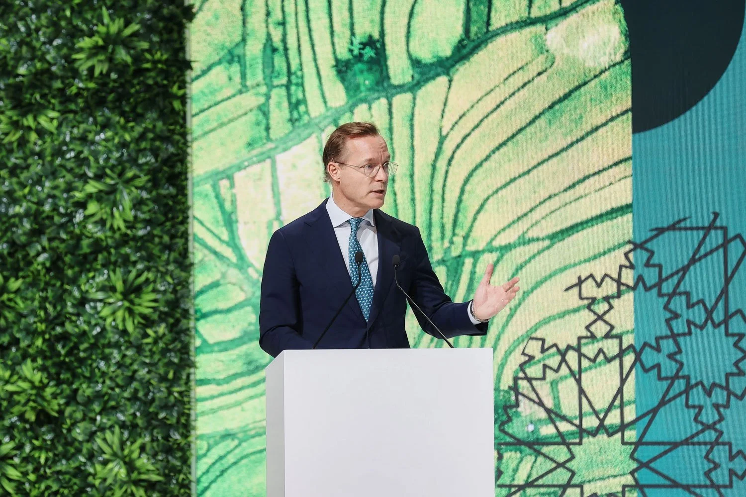 Business leader delivering keynote speech on stage during a corporate conference presentation.