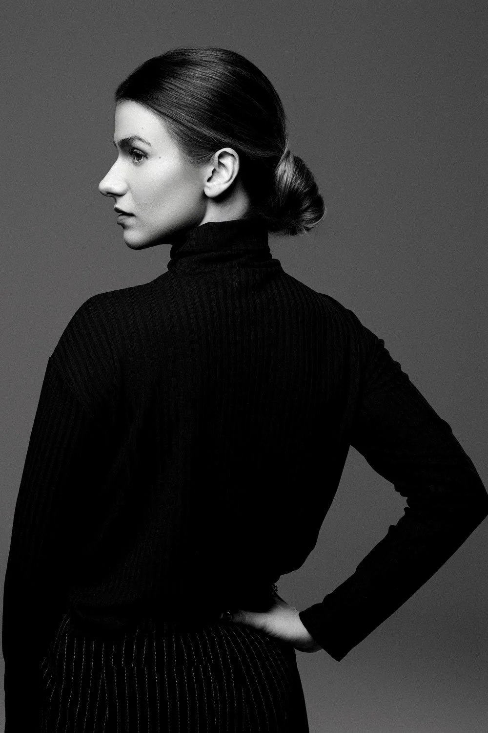 Black and white artistic portrait of woman photographed in studio with dramatic lighting.
