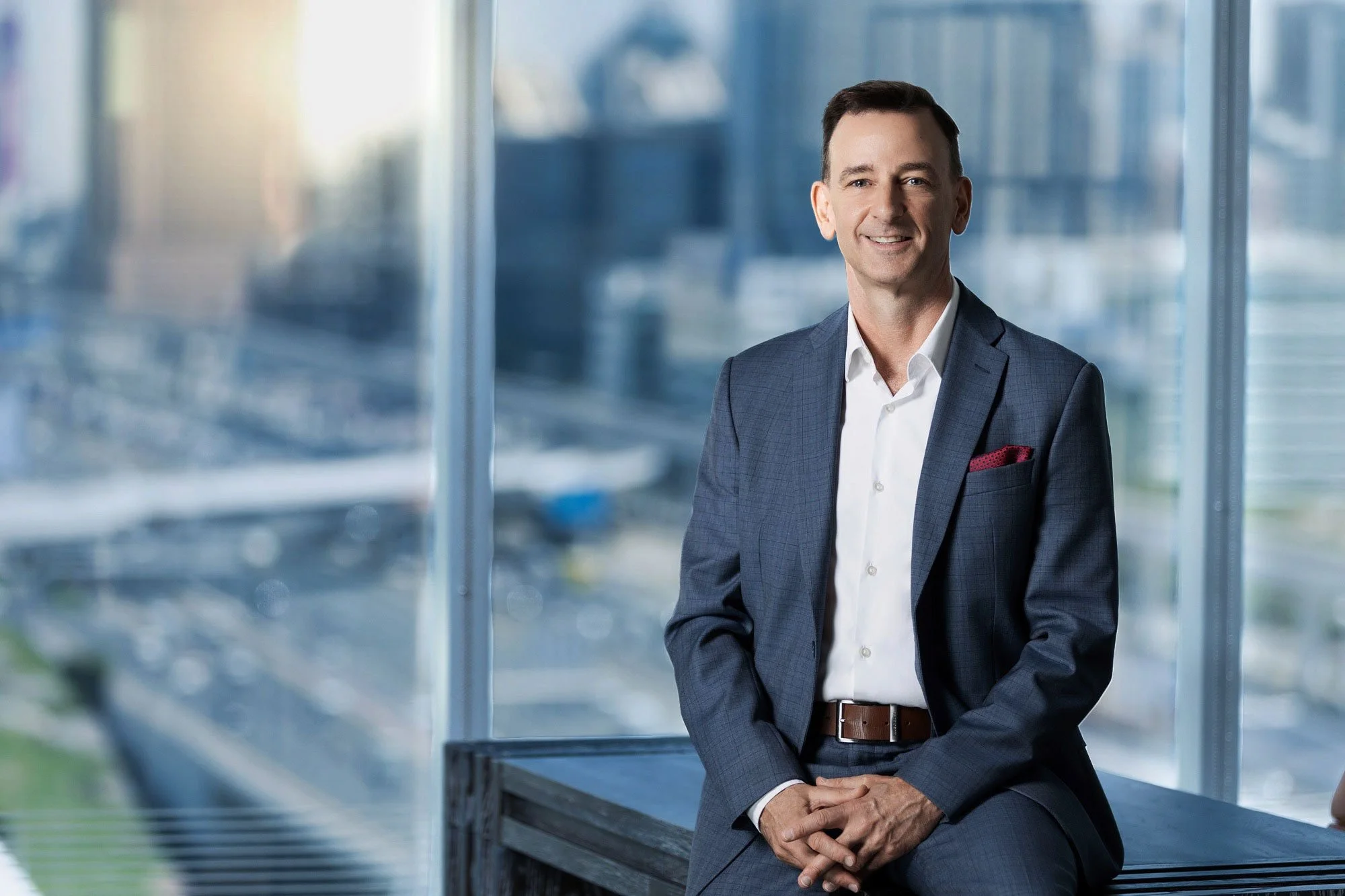 Business portrait photographed in office with city skyline background in Dubai.