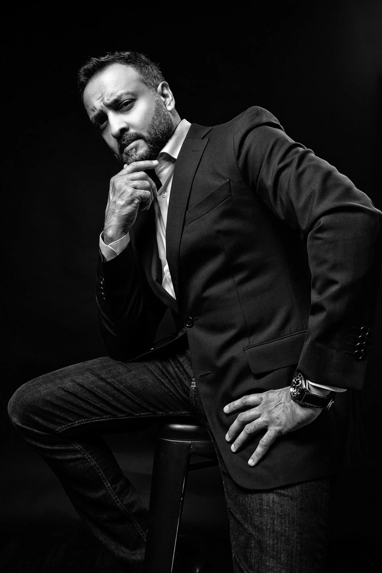 Black and white artistic portrait of man photographed in studio with dramatic lighting.