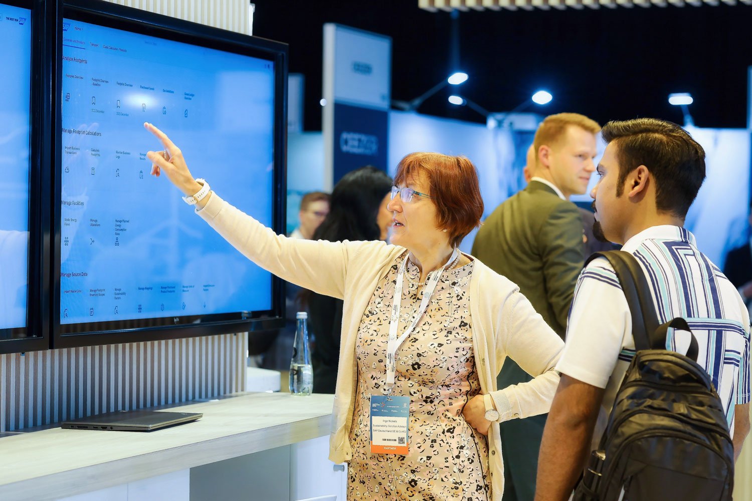 Female technology professional presenting product information at corporate exhibition booth.
