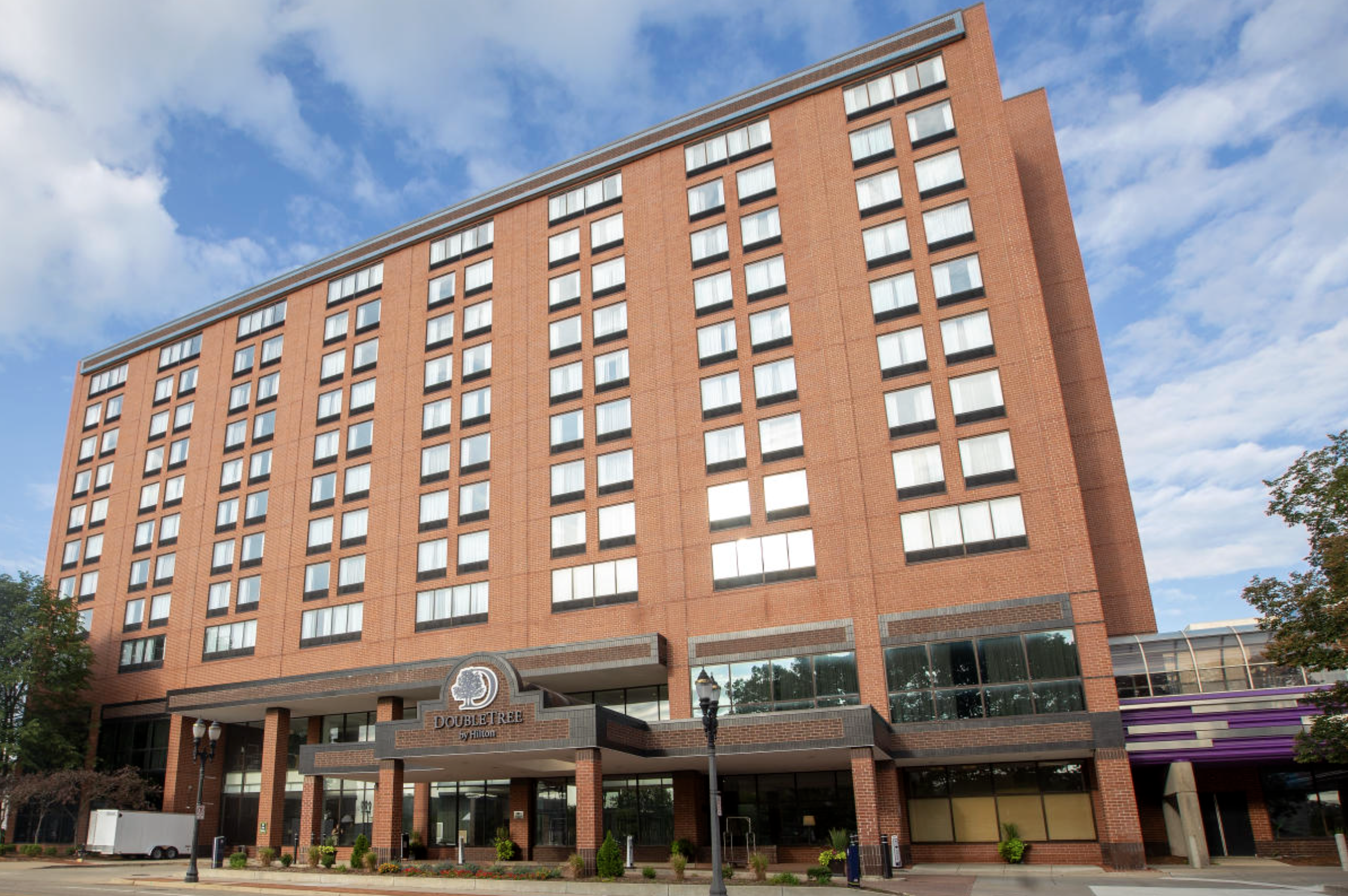 A tall red brick Hilton hotel building with multiple windows and a sign that reads "DoubleTree by Hilton."