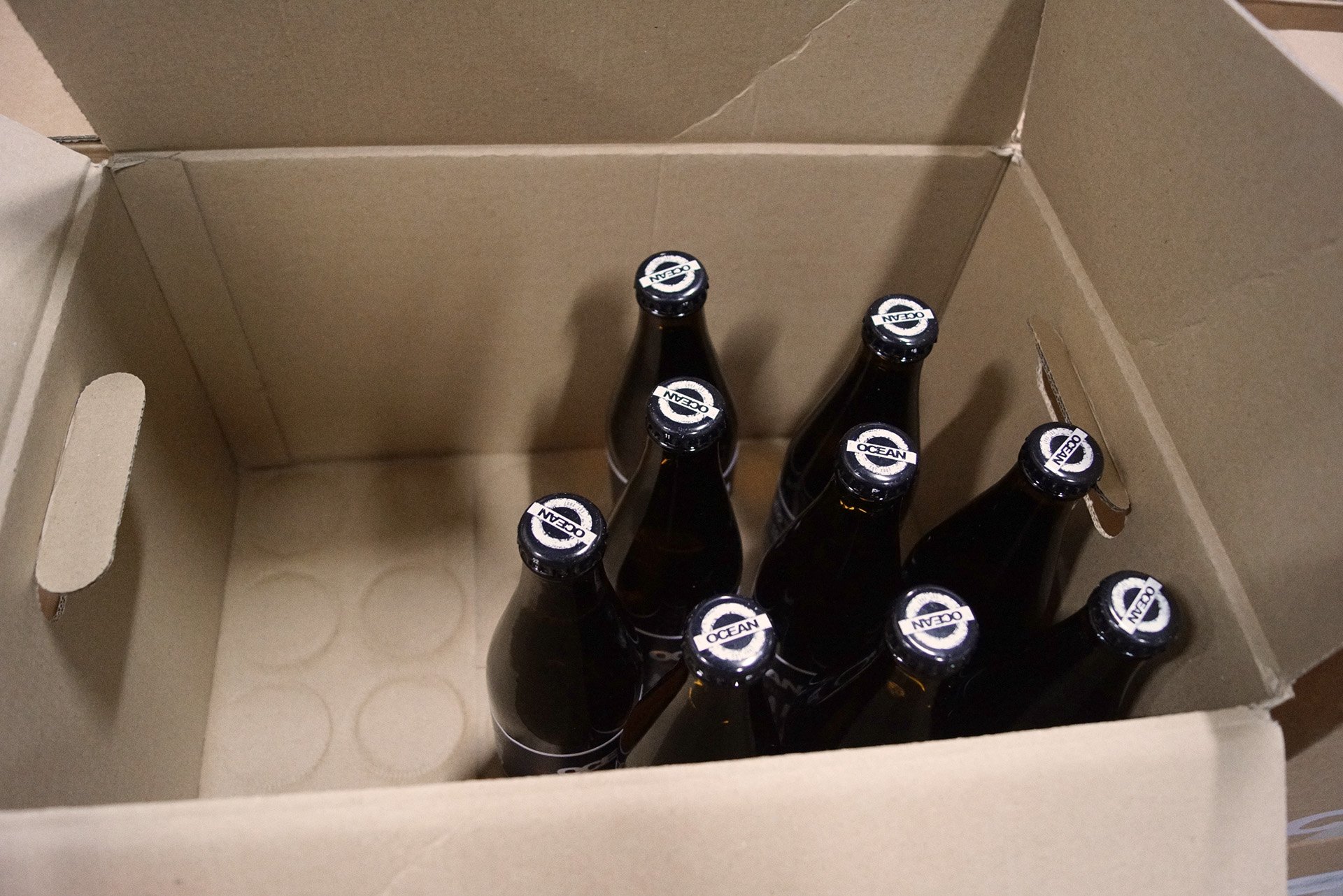 Sju mörka ocean ölflaskor i en öppen kartong.